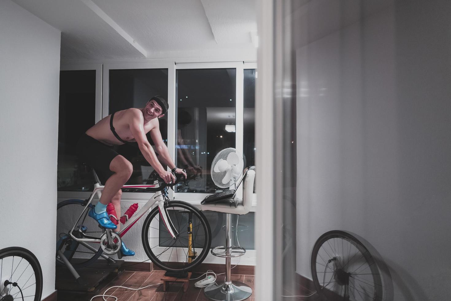 Man cycling on the machine trainer he is exercising in the home at night playing online bike racing game photo