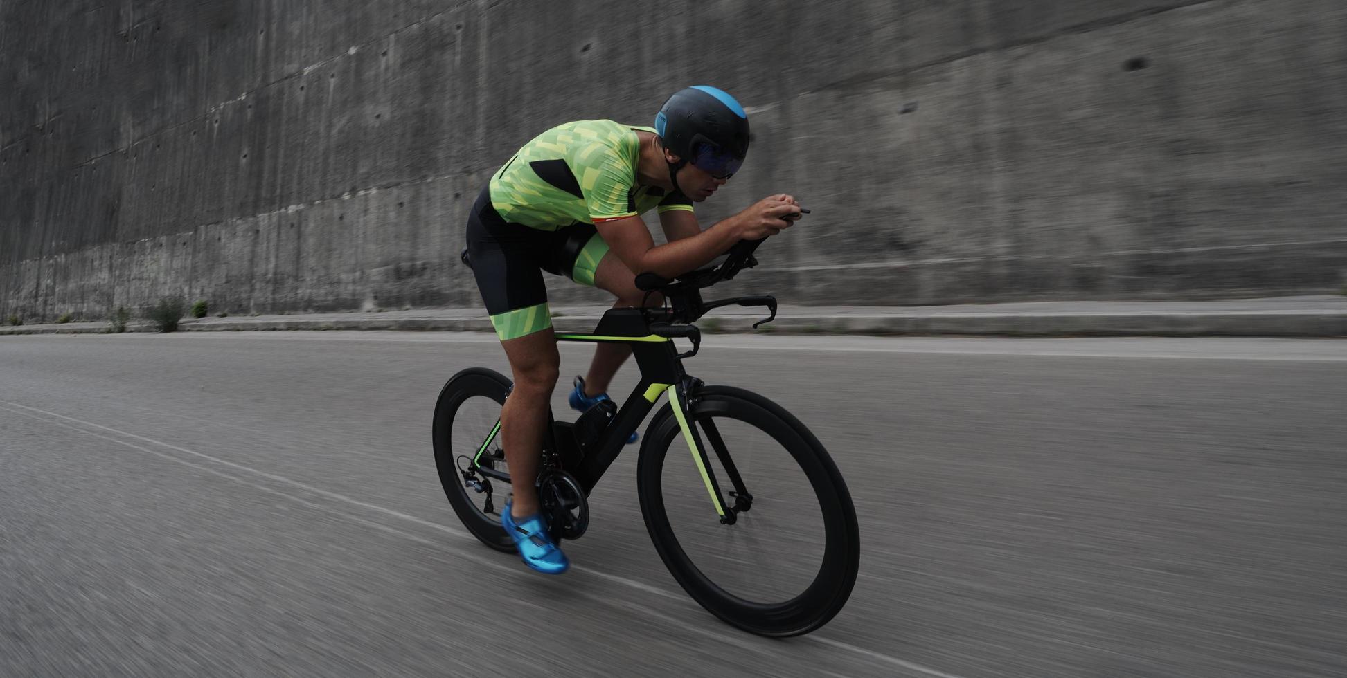 atleta de triatlón montando en bicicleta en el entrenamiento matutino foto