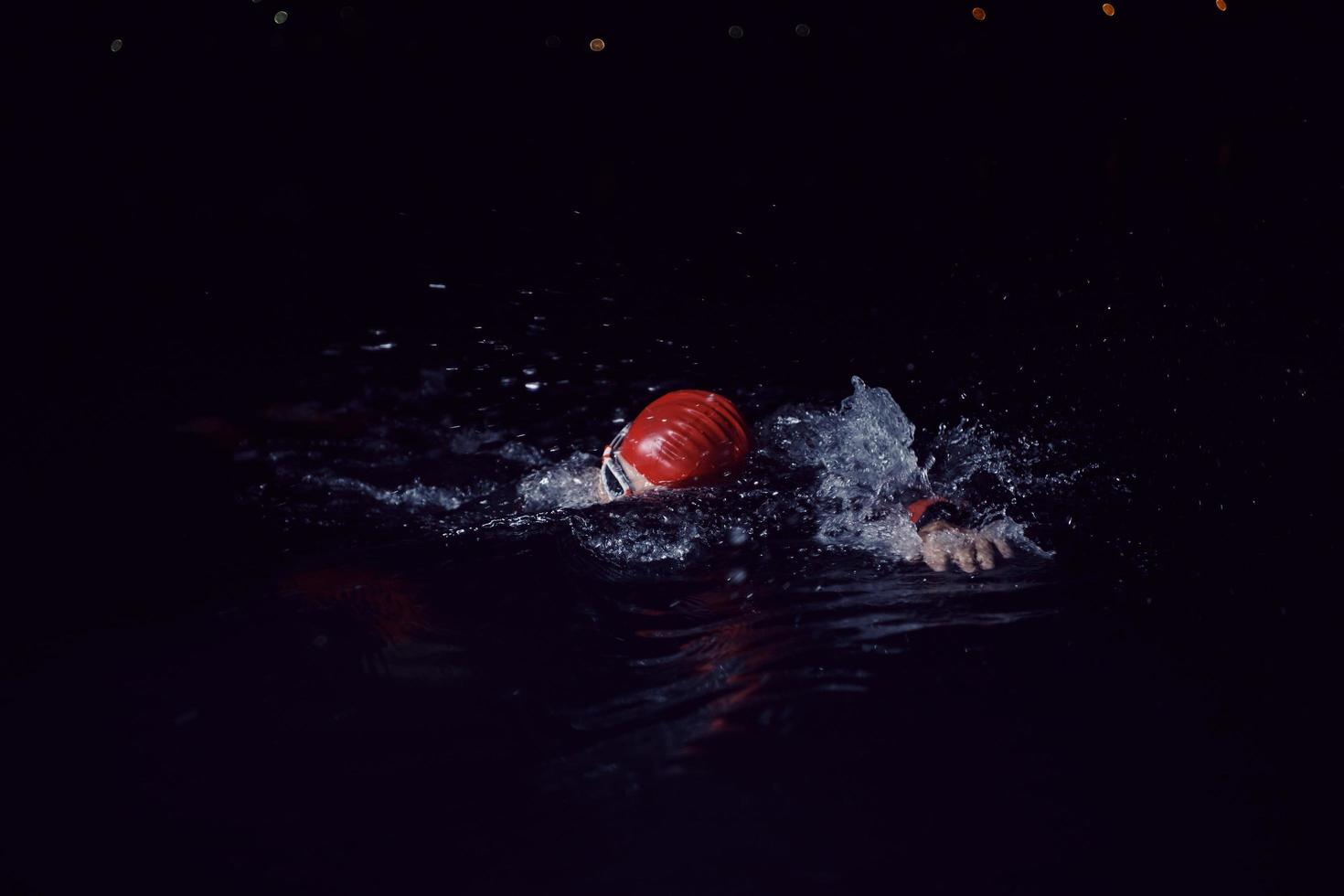 atleta de triatlón nadando en la noche oscura con traje de neopreno foto