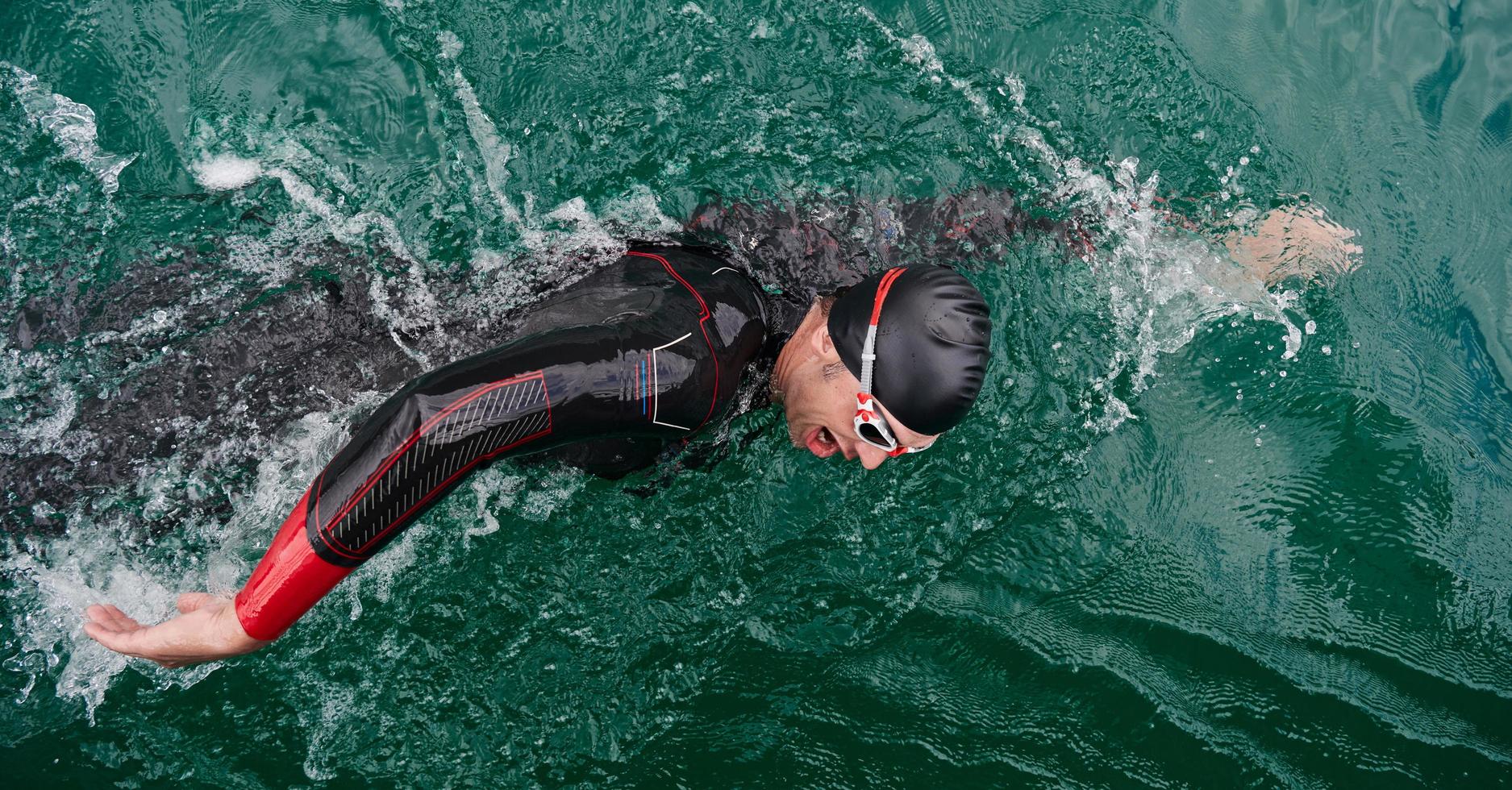 triathlon athlete swimming on lake wearing wetsuit photo