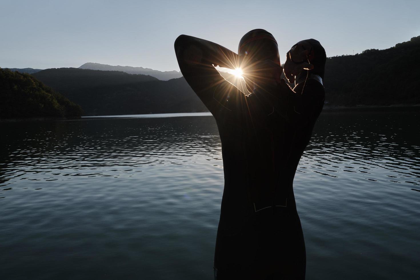 triathlon athlete starting swimming training on lake photo