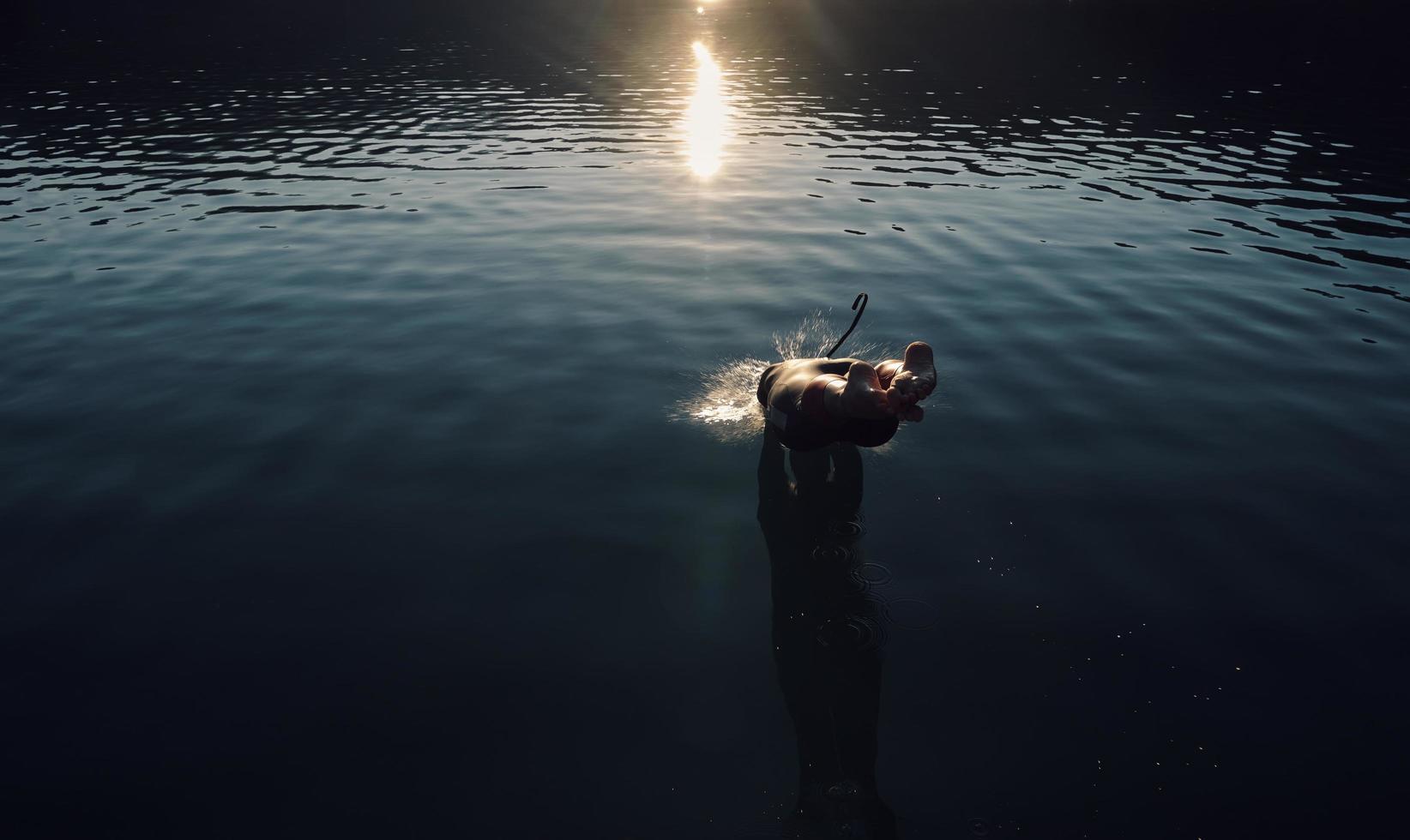 atleta de triatlón saltando al agua y comenzando con el entrenamiento foto