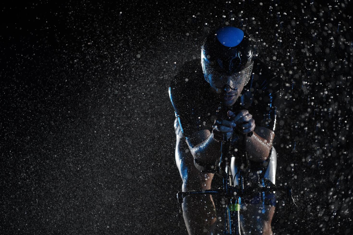 atleta de triatlón montando bicicleta rápido en una noche lluviosa foto