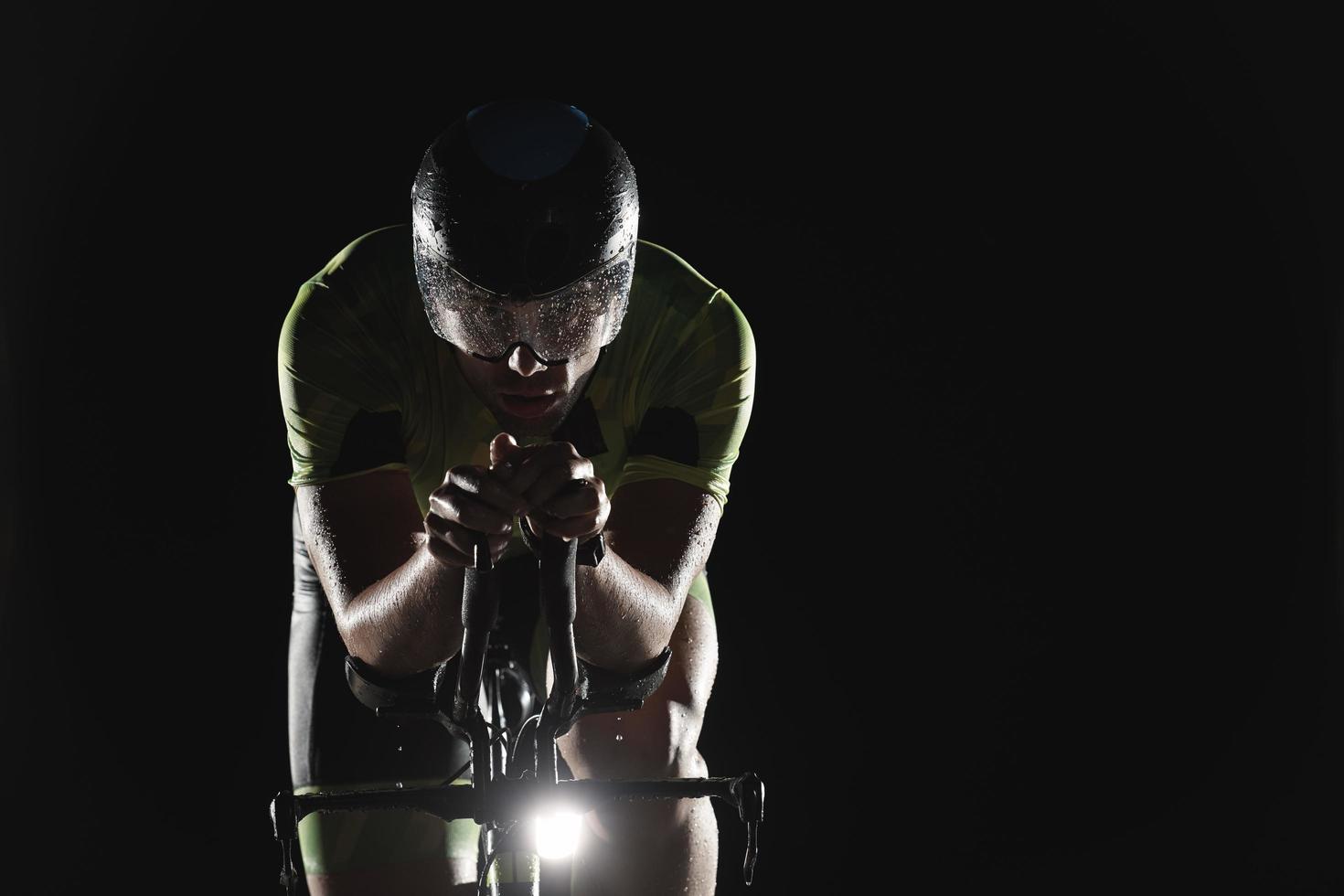 atleta de triatlón montando bicicleta rápido por la noche foto