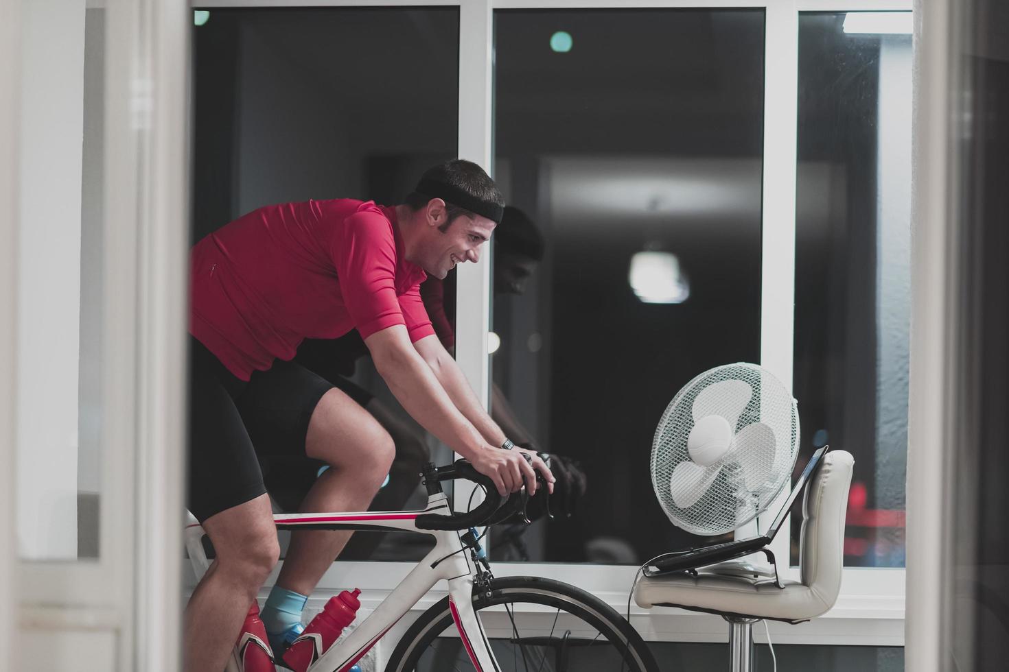 Man cycling on the machine trainer he is exercising in the home at night playing online bike racing game photo