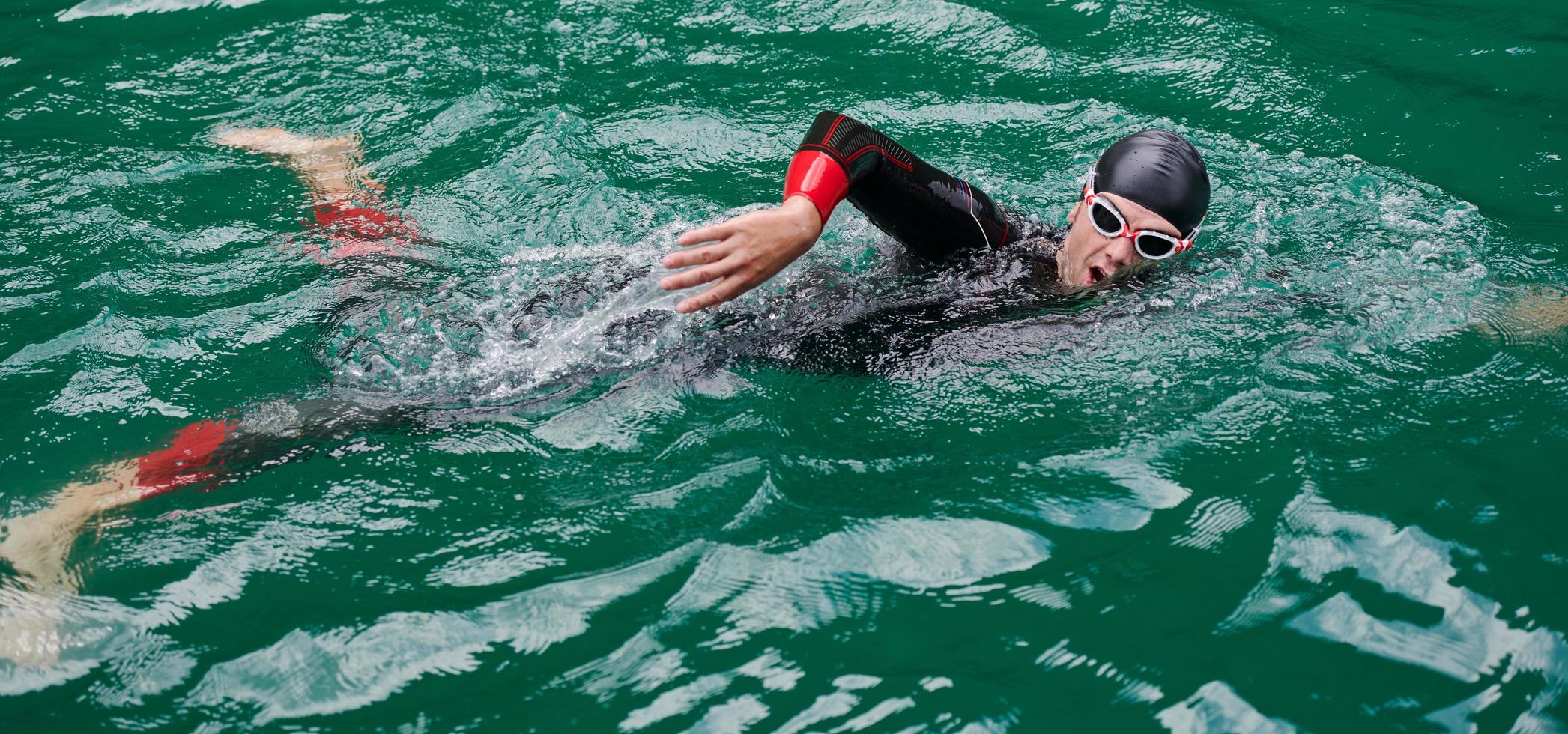 triathlon athlete swimming on lake wearing wetsuit photo