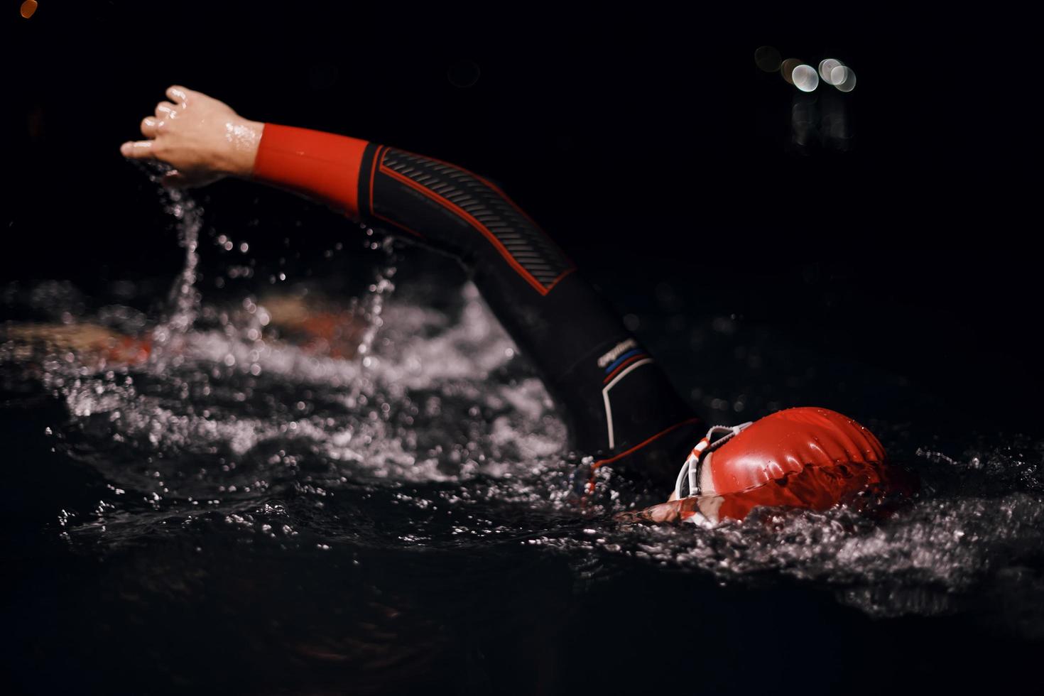 triathlon athlete swimming in dark night  wearing wetsuit photo