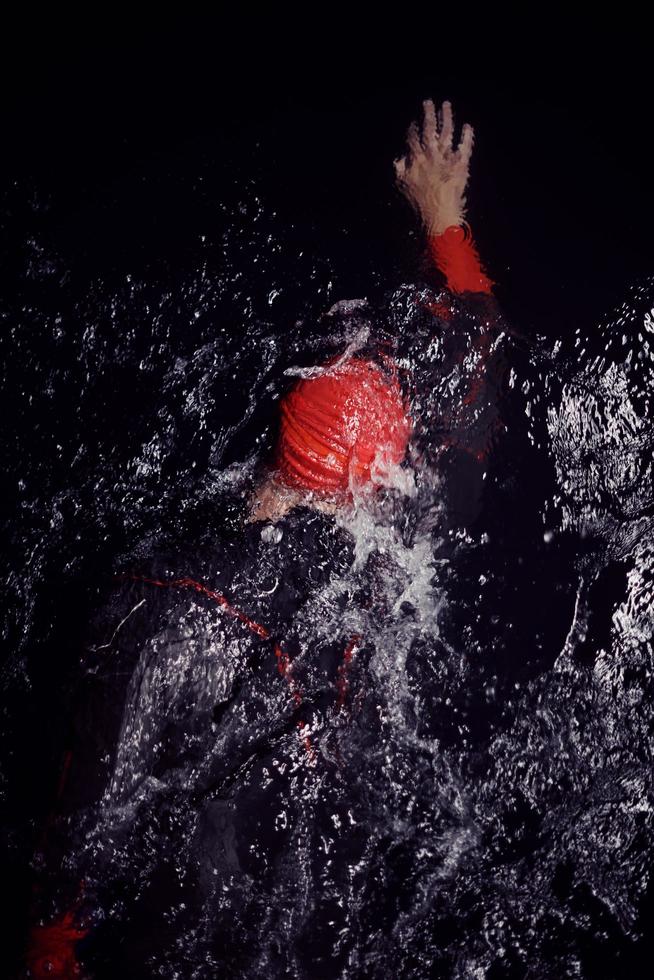 triathlon athlete swimming in dark night  wearing wetsuit photo