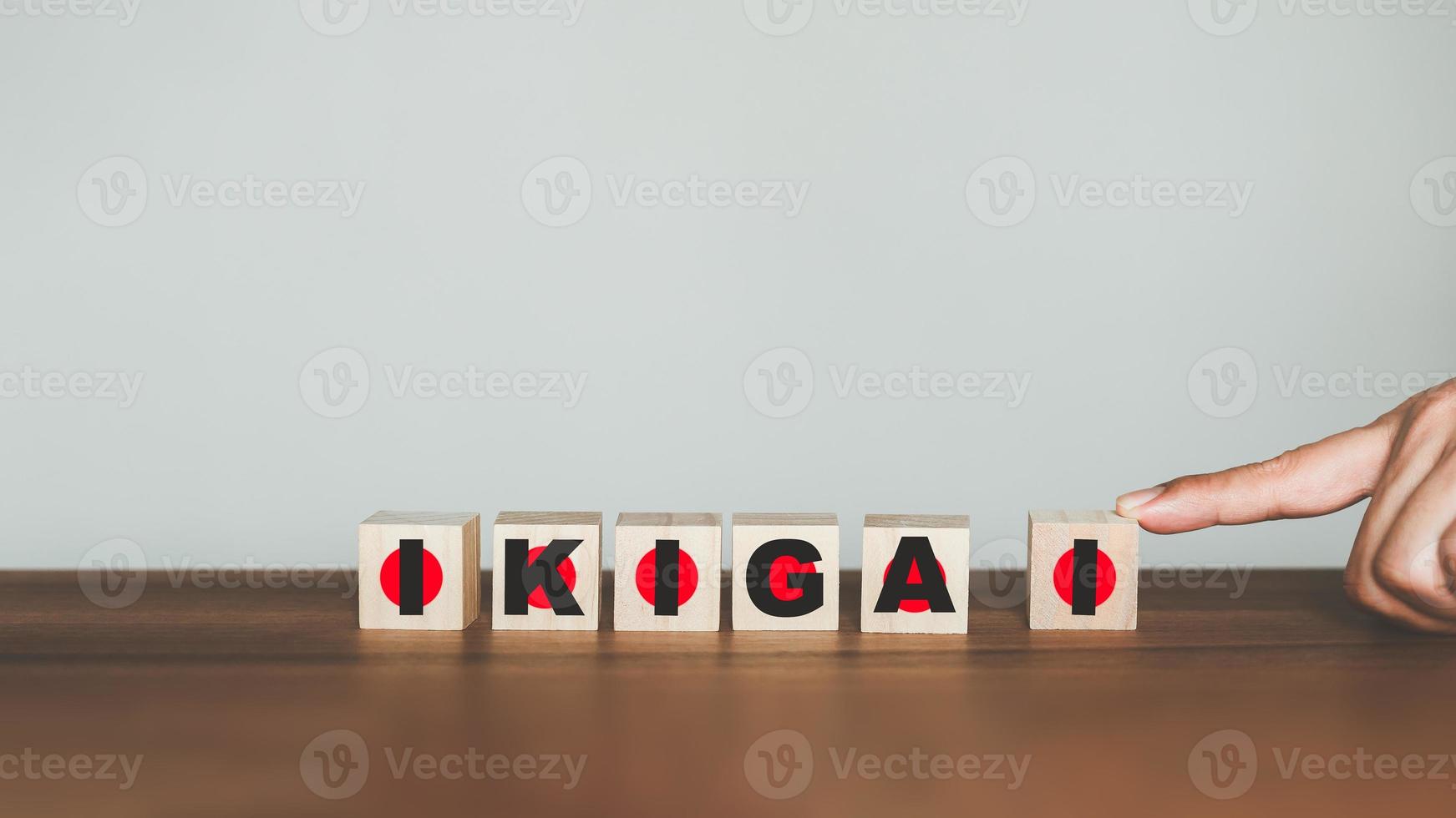 hand scrolling the word words to get the word IKIGAI on wooden cubes block. Japanese lifestyle concept. photo