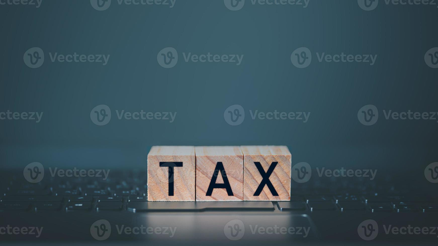 Tax words on wooden cube block which is placed on a laptop. Concept of online tax filling. photo