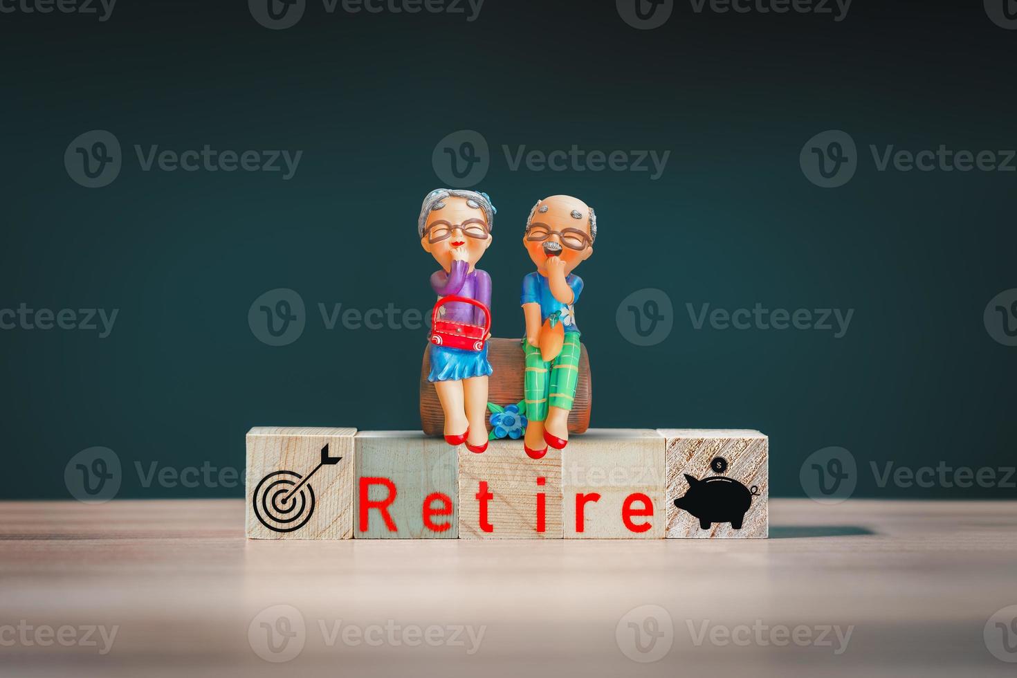 Elderly clay doll on a wooden cube block with the word retired on a wooden table. Retirement Planning Ideas. photo
