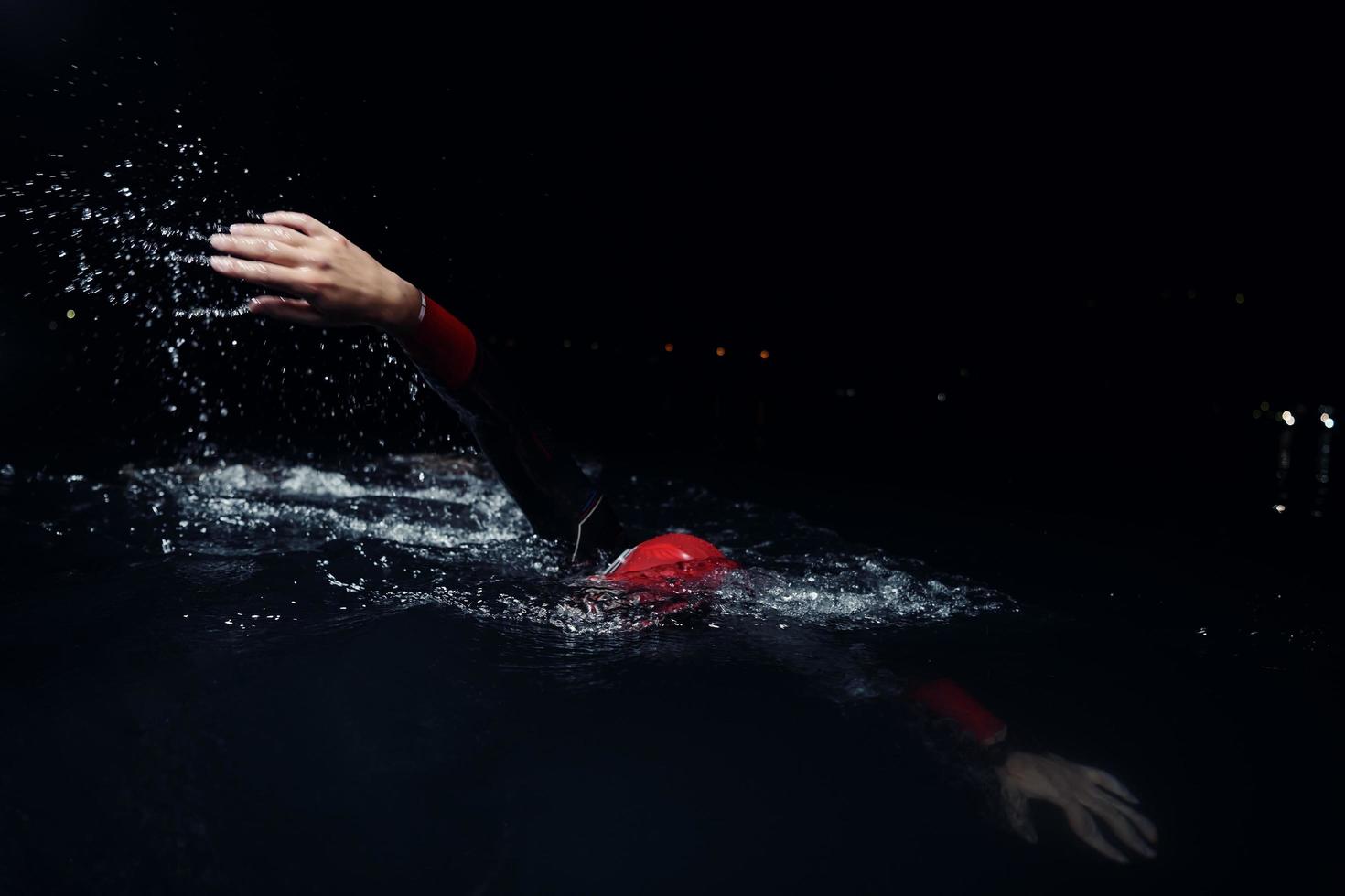 triathlon athlete swimming in dark night  wearing wetsuit photo