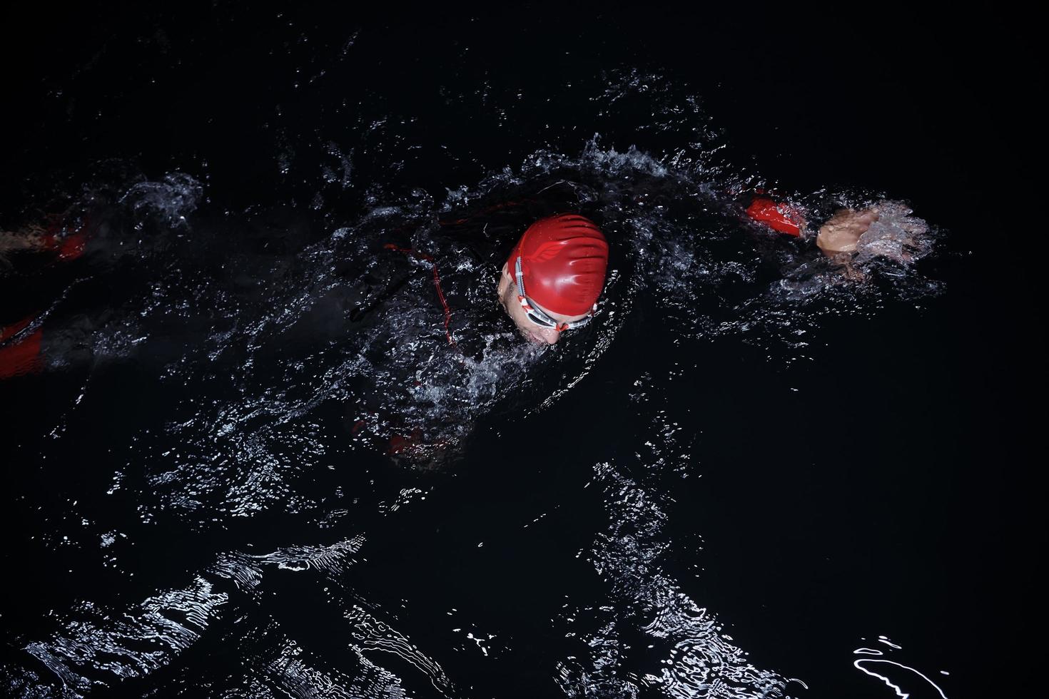 atleta de triatlón nadando en la noche oscura con traje de neopreno foto