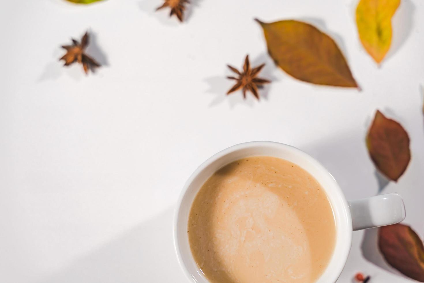 concepto de otoño o invierno con hojas de pino y arce, taza de café, canela y bufanda, puesta plana, vista superior. foto