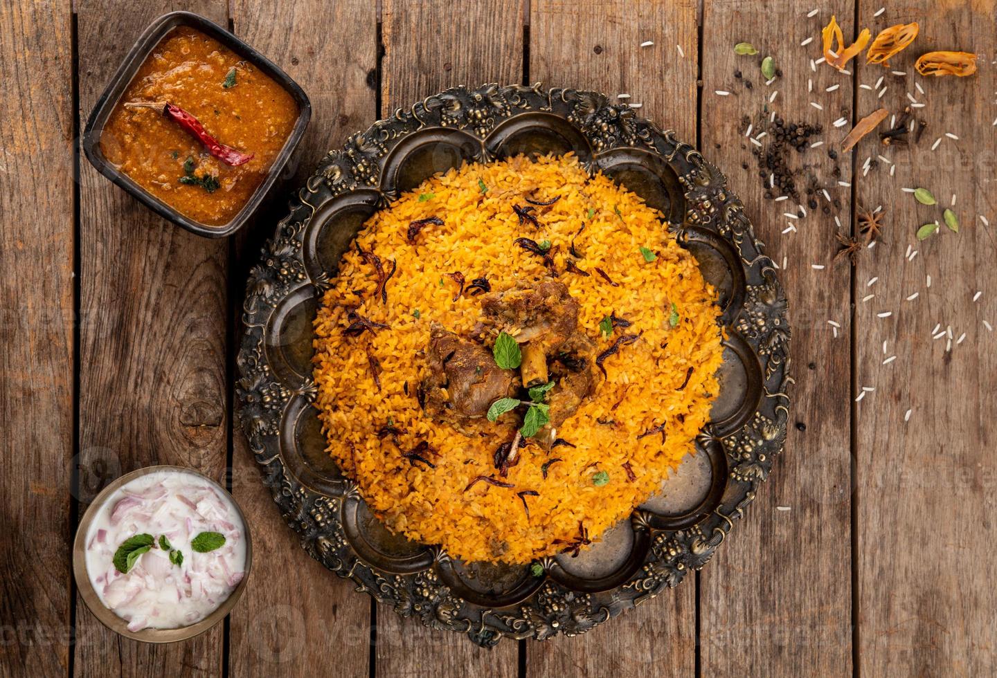 Mutton Biryani  made with highly seasoned rice and spices marinated meat cooked with its own juices and aromatic Indian spices and served with brinjal gravy and onion raitha as accompaniments. photo