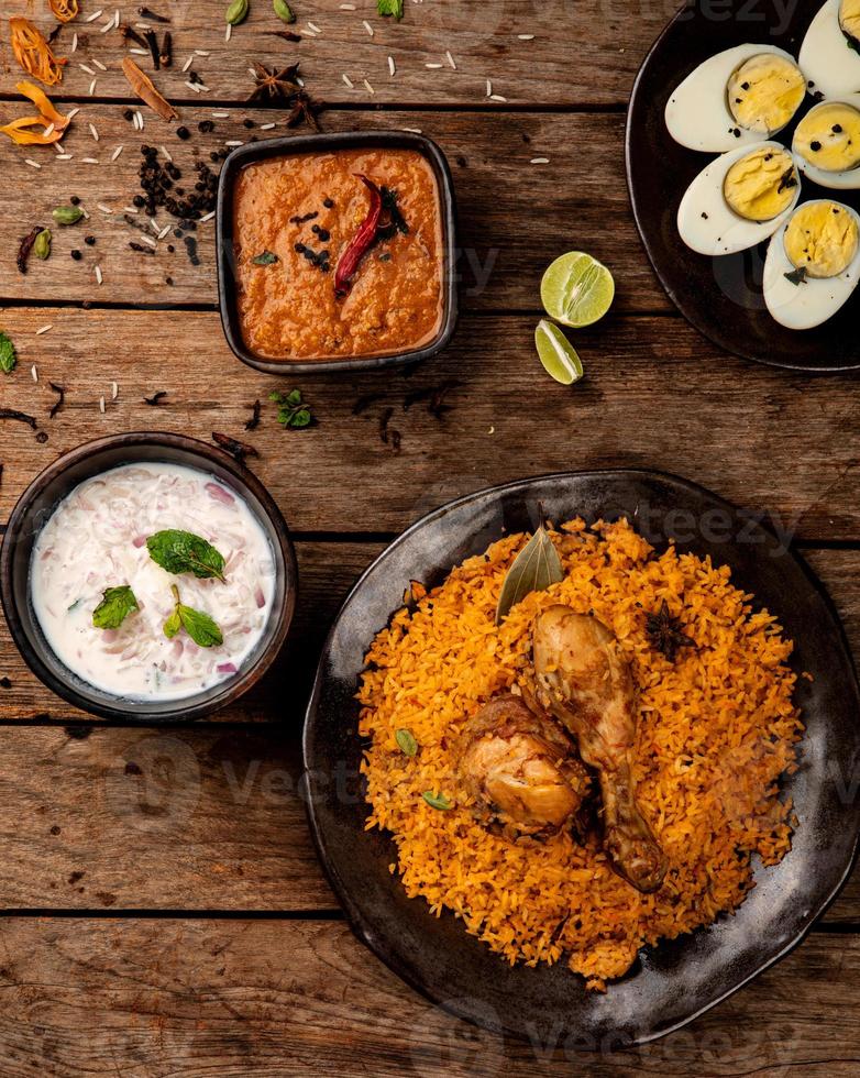 Chicken biryani an Indian dish that comes in set of rice-based food made with spices ,rice and chicken and served with brinjal gravy and onion raitha as accompaniments. photo