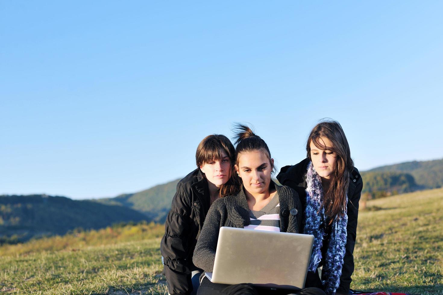 grupo de adolescentes trabajando en una laptop al aire libre foto