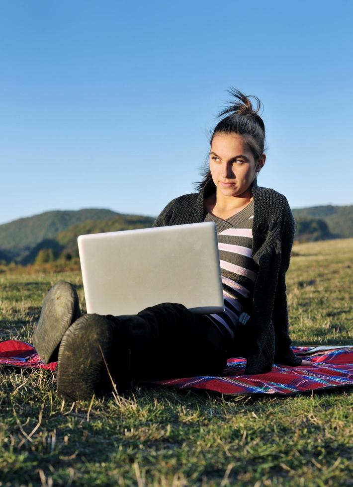 Joven adolescente trabaja en una laptop al aire libre foto