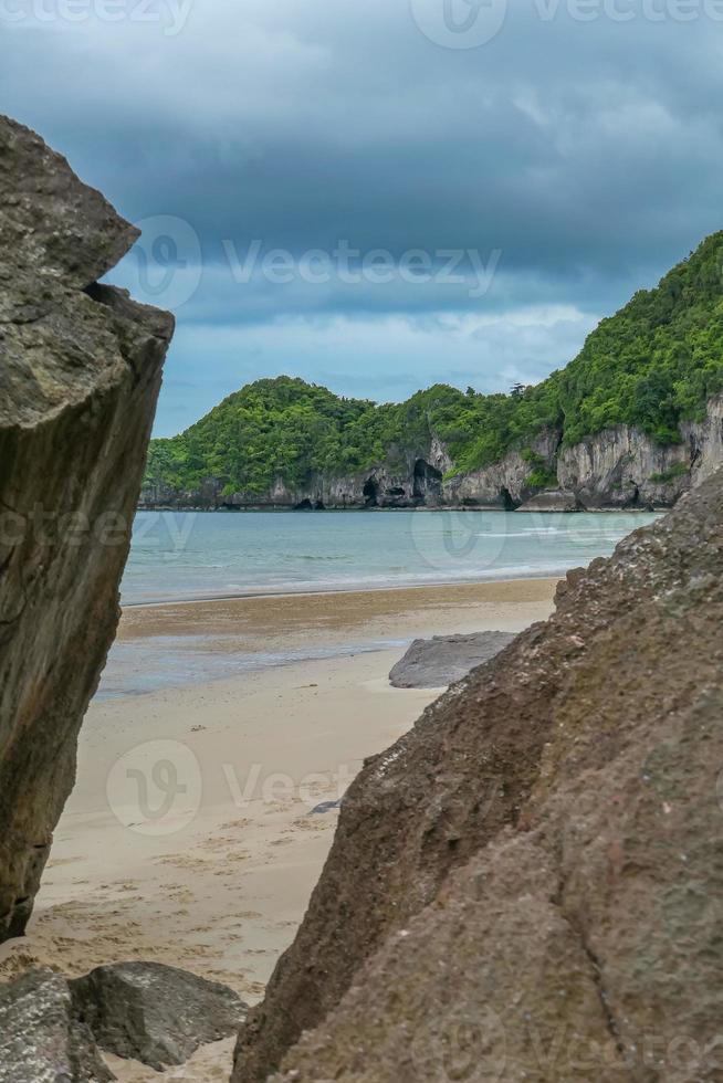 Seaside rocks on the beautiful beach in the morning with rain cloud. photo