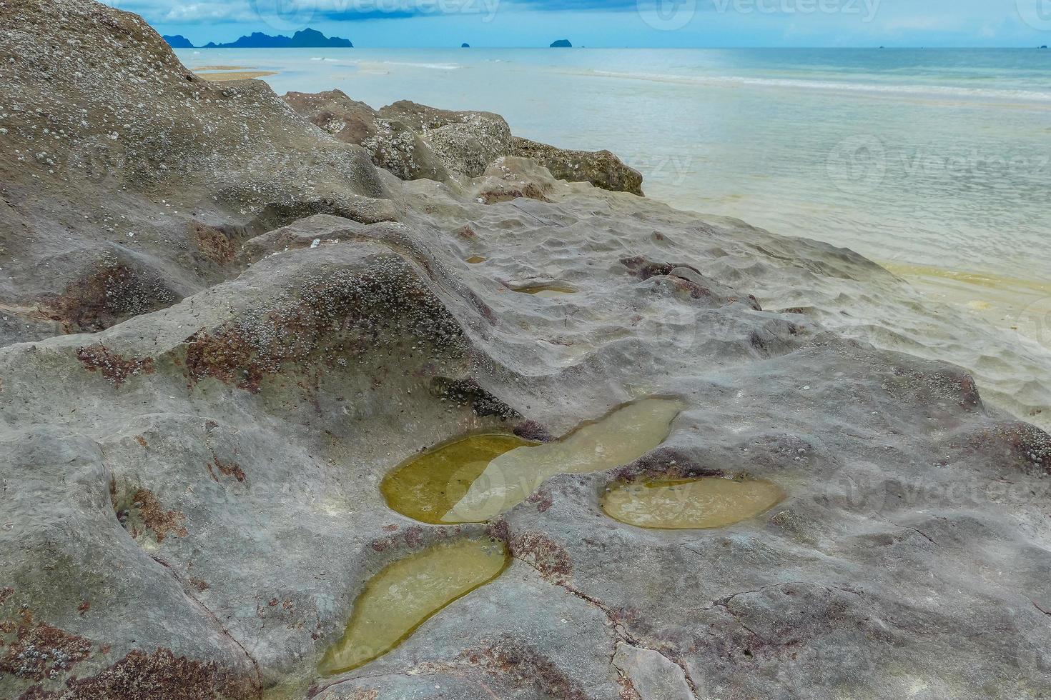 Seaside rocks on the beautiful beach in the morning with rain cloud. photo