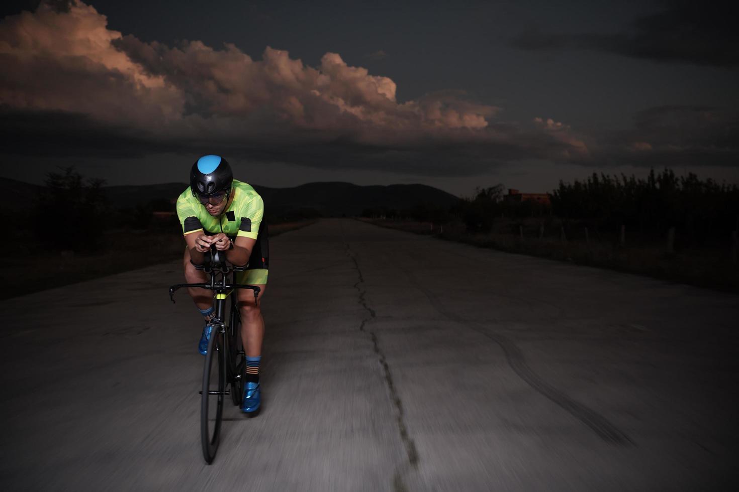 triathlon athlete riding bike fast  at night photo