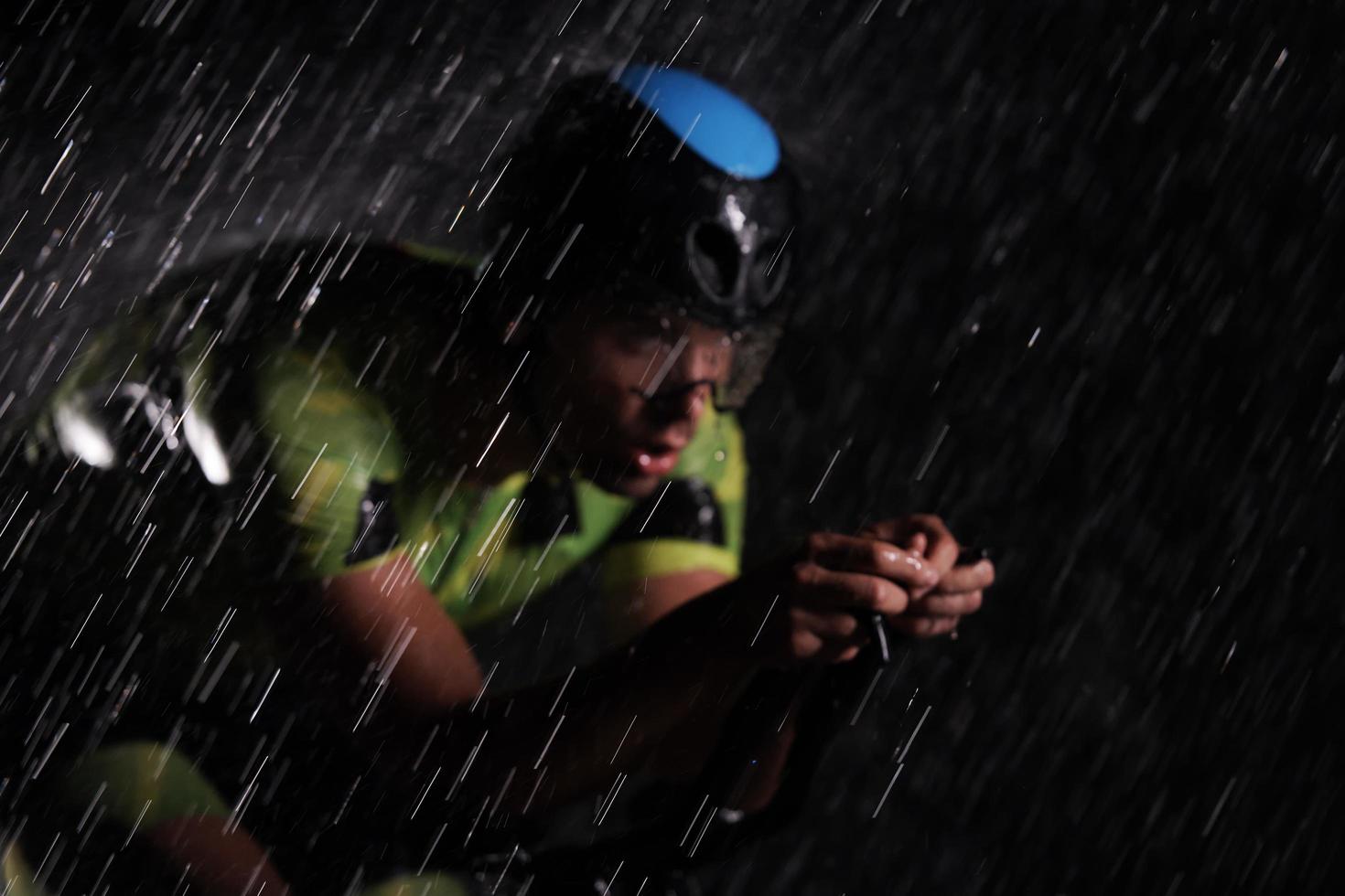 triathlon athlete riding bike  fast on rainy night photo
