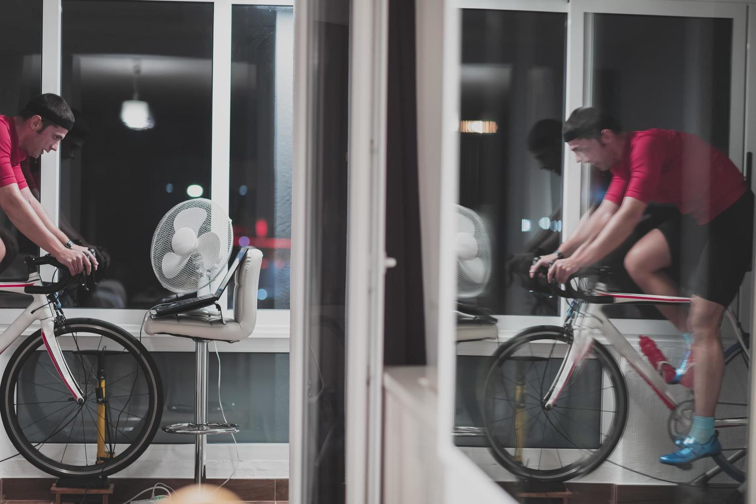 Man cycling on the machine trainer he is exercising in the home at night playing online bike racing game photo