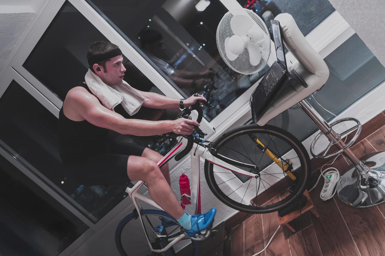 Man cycling on the machine trainer he is exercising in the home at night playing online bike racing game photo