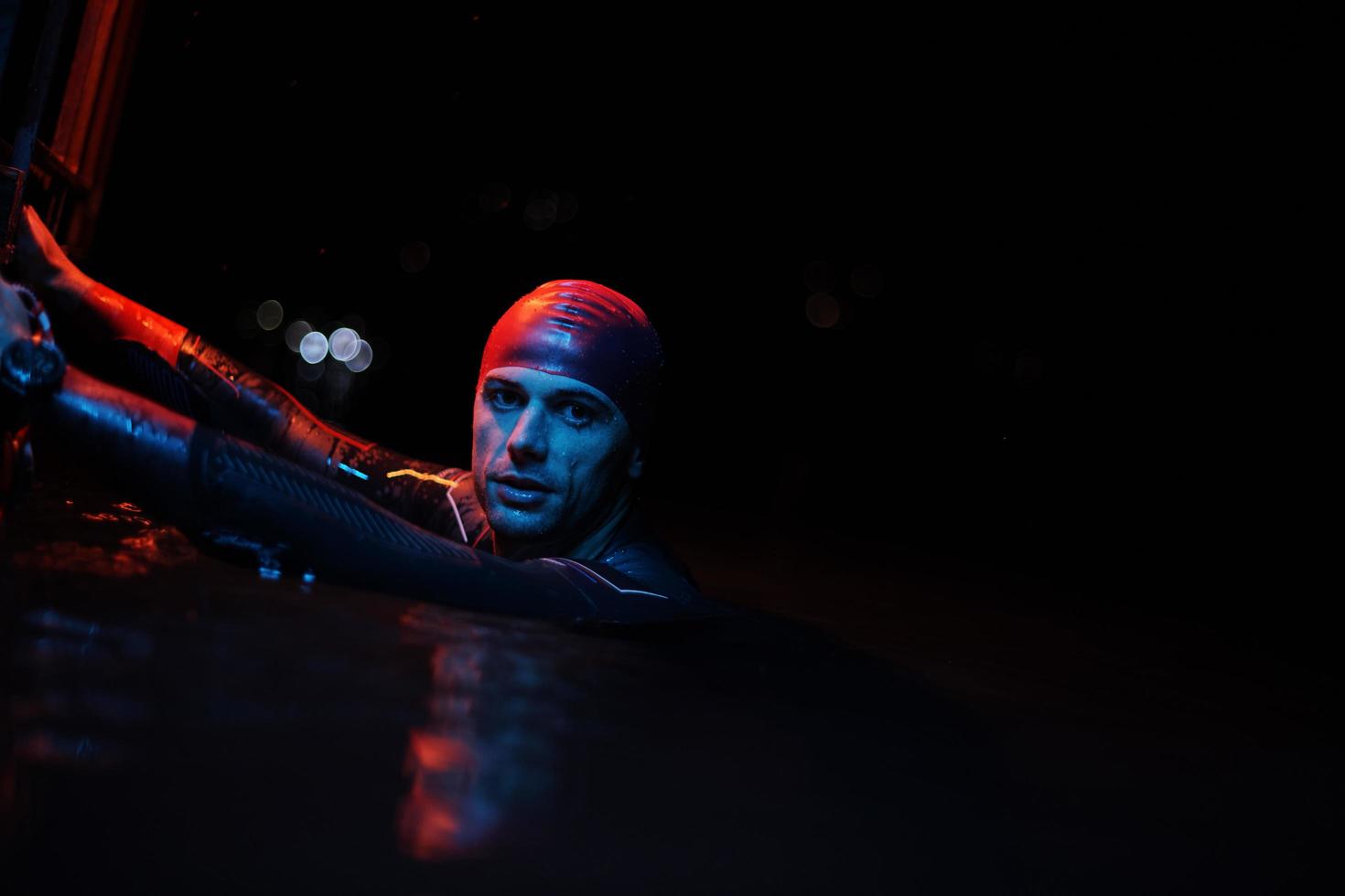 authentic triathlete swimmer having a break during hard training on night neon gel light photo