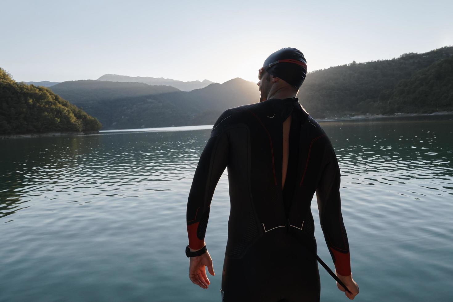 triathlon athlete starting swimming training on lake photo
