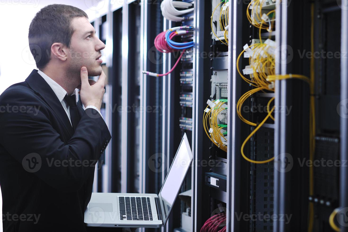 businessman with laptop in network server room photo