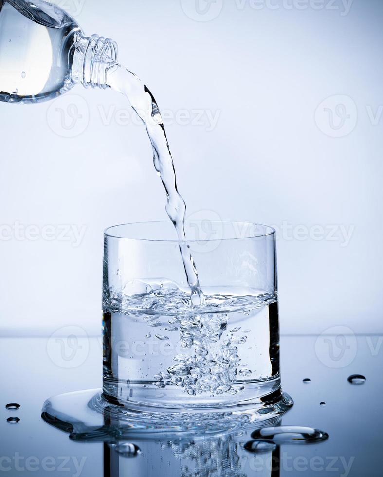 Pouring fresh pure water from bottle into a glass on the table with