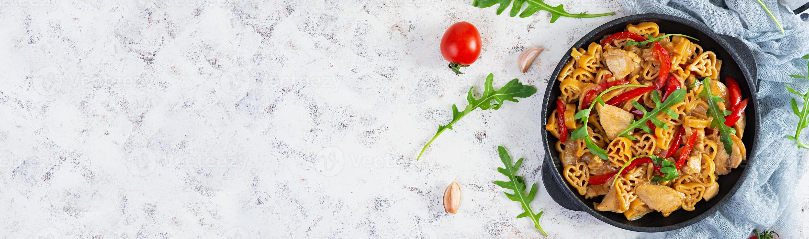 Tasty pasta in tomato sauce with chicken, pepper and herbs on white background. Top view photo
