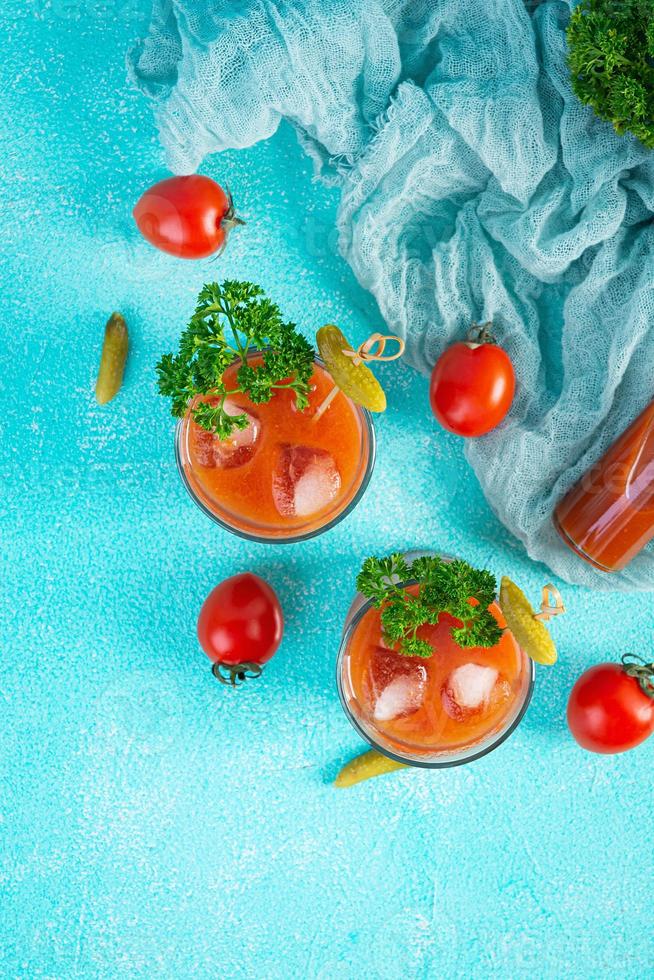 Alcohol cocktail Bloody Mary on blue background. Classic cocktail with tomato juice and vodka. Top view photo