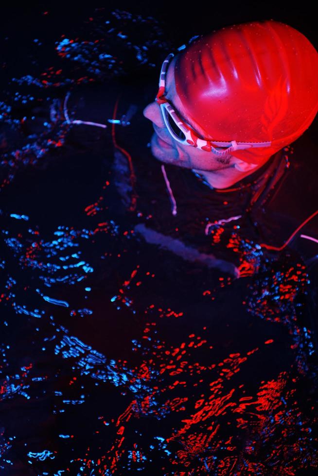 authentic triathlete swimmer having a break during hard training on night neon gel light photo