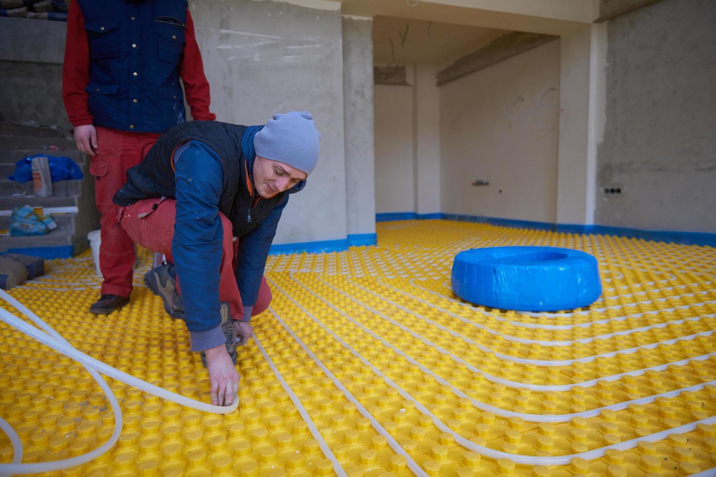 workers installing underfloor heating system photo