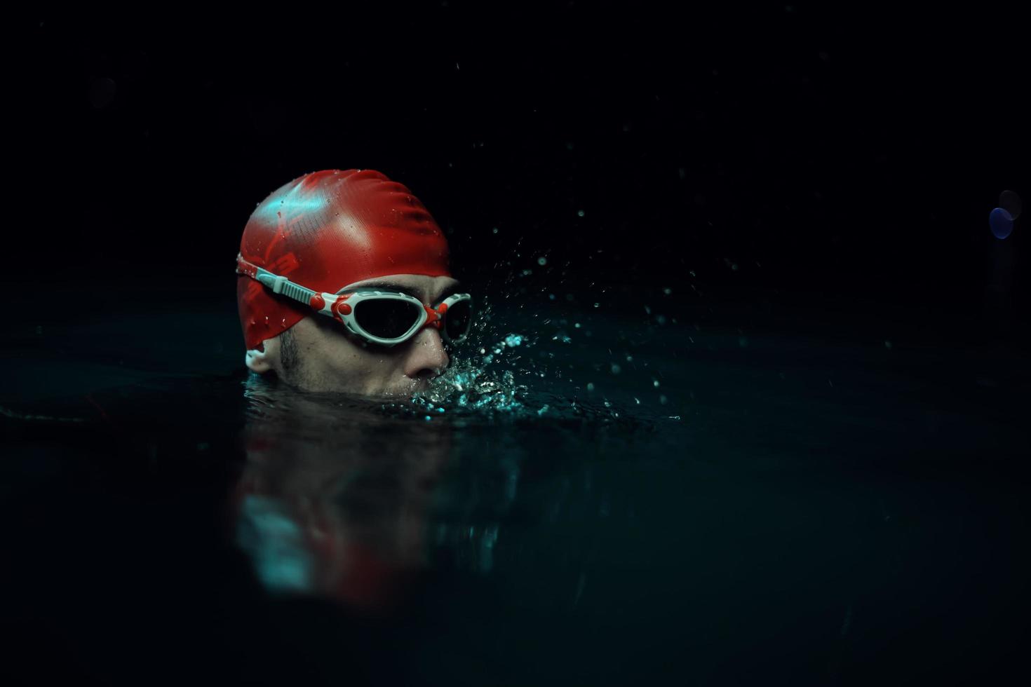 authentic triathlete swimmer having a break during hard training on night neon gel light photo