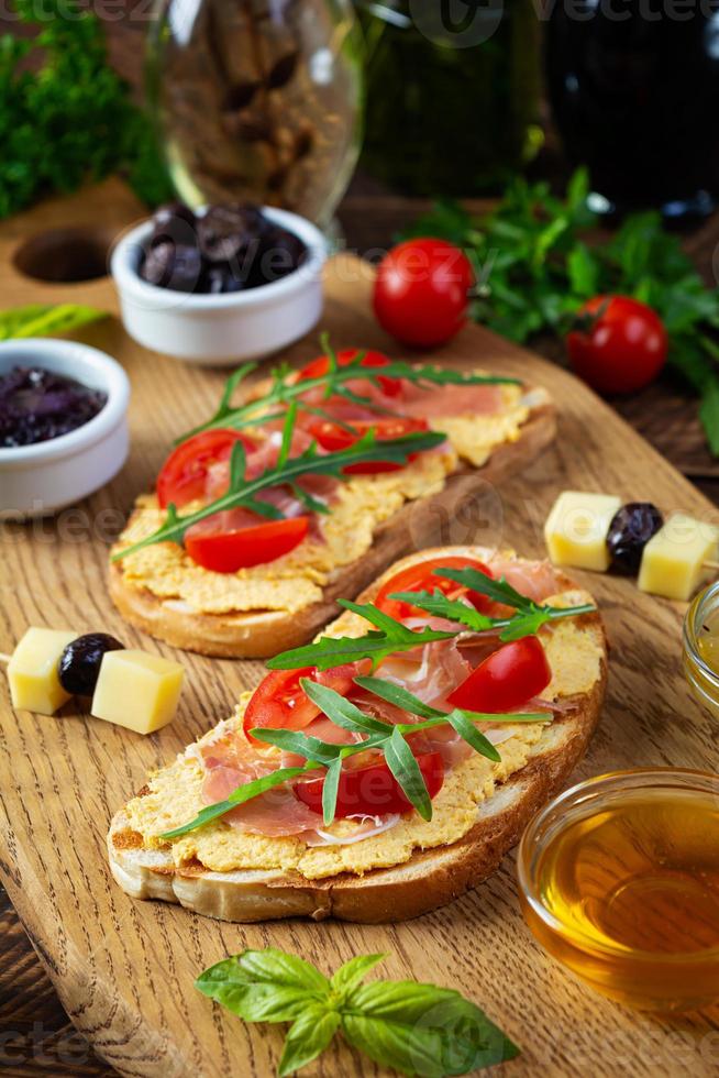 bruschetta a la parrilla con rillettes de pollo, jamón y hierbas. deliciosa tostada con paté de pollo y diferentes aperitivos foto