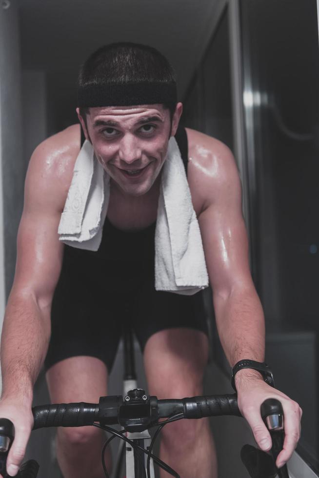 Man cycling on the machine trainer he is exercising in the home at night playing online bike racing game photo