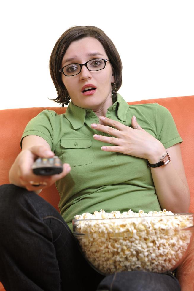 mujer joven come palomitas de maíz y ve la televisión foto