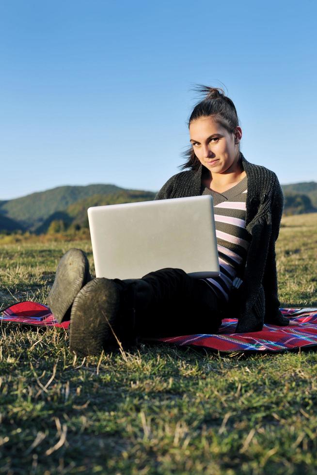 Joven adolescente trabaja en una laptop al aire libre foto