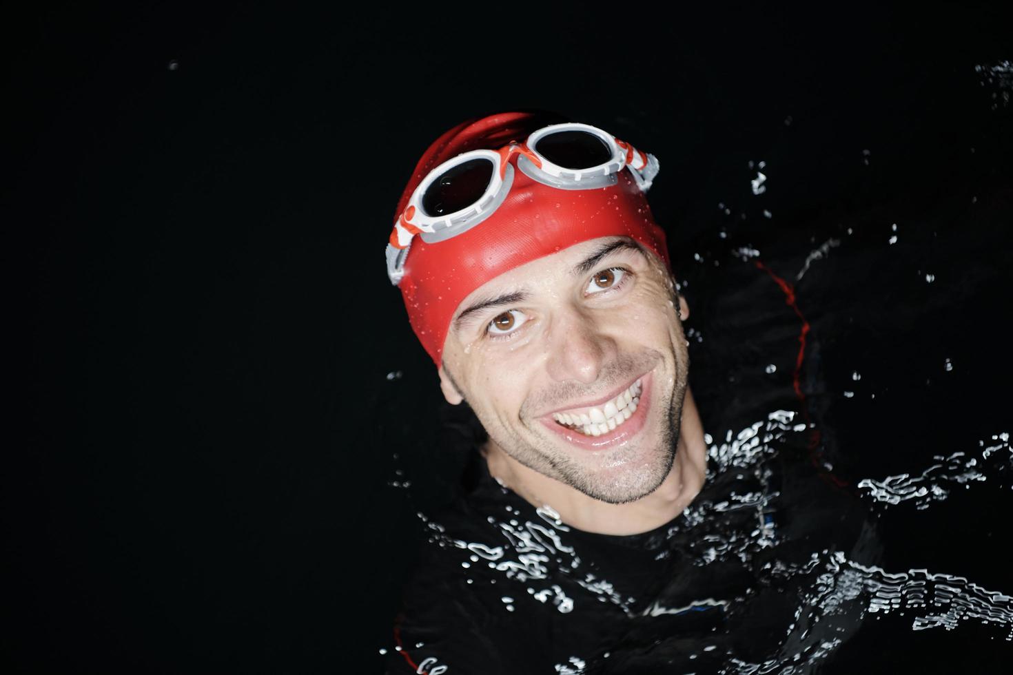 nadador triatleta auténtico que tiene un descanso durante el entrenamiento duro en la noche foto