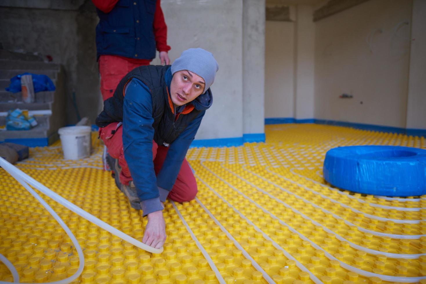 workers installing underfloor heating system photo