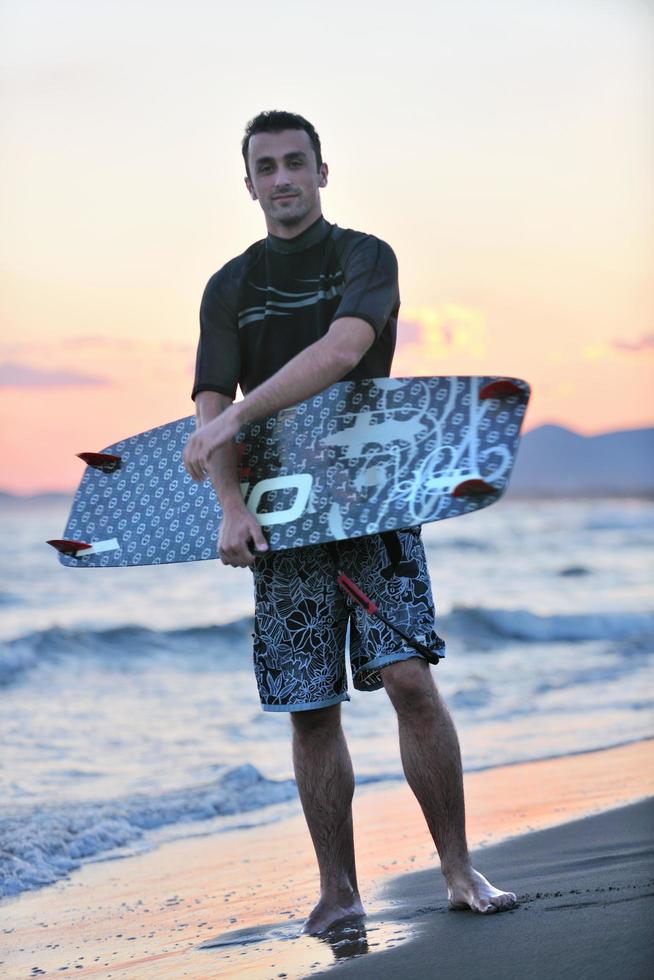 Portrait of a young  kitsurf  man at beach on sunset photo