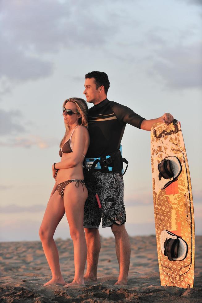 surf couple posing at beach on sunset photo
