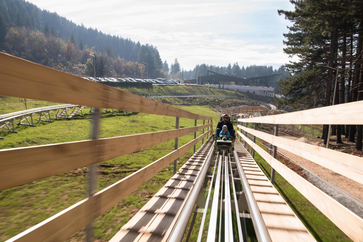 father and son enjoys driving on alpine coaster photo