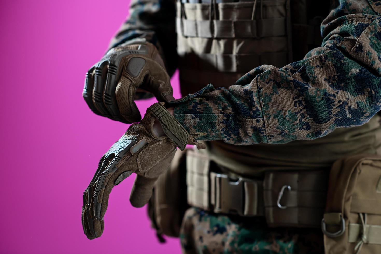 primer plano de las manos del soldado poniendo guantes protectores de batalla fondo rosa foto