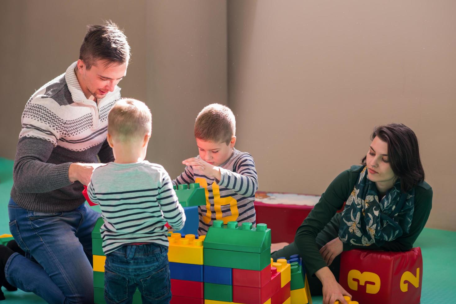 padres jóvenes y niños divirtiéndose en la sala de juegos para niños foto