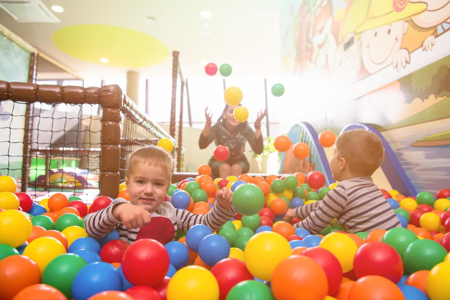 young mom playing with kids in pool with colorful balls photo