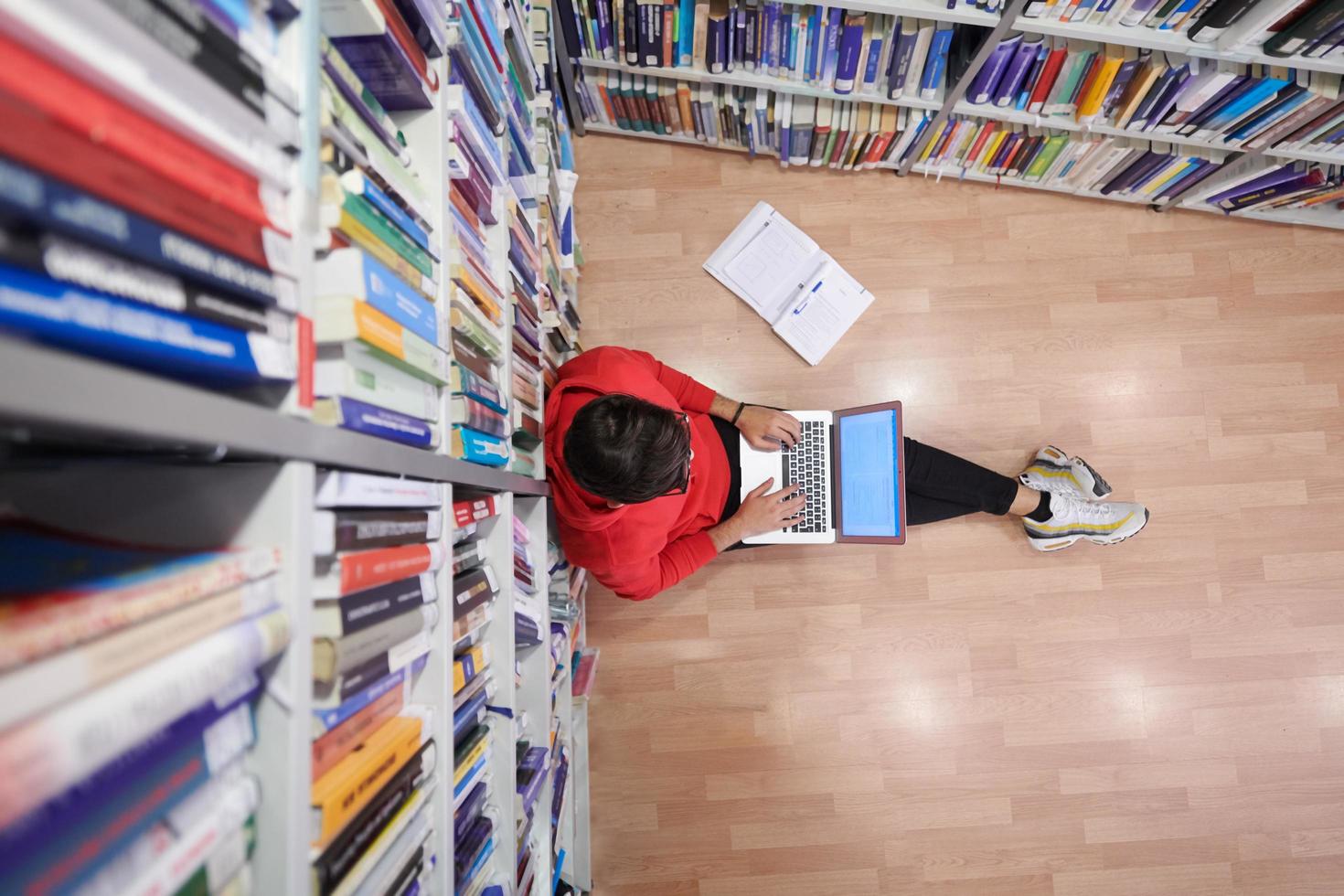 the students uses a notebook, laptop and a school library photo